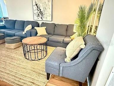 A living room features a blue sofa, a matching armchair, and a round wire coffee table — 709 HICKORY LANE, BRADENTON, FL