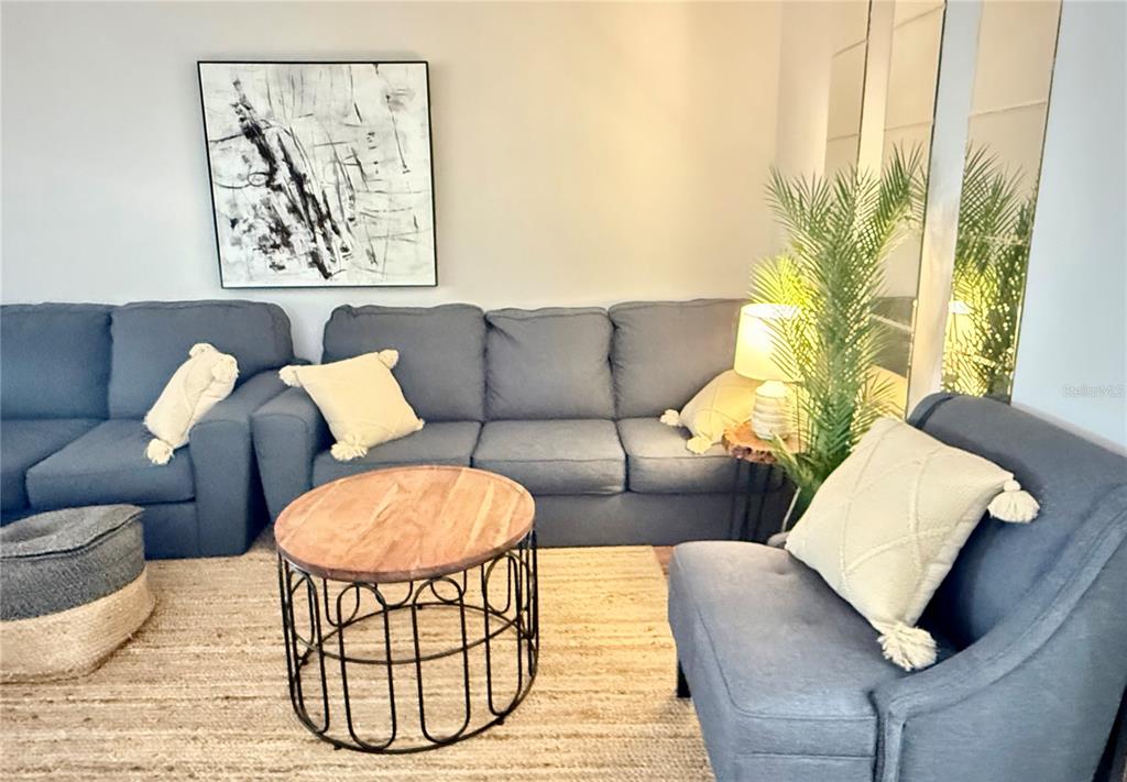A living room features a blue sofa, a matching armchair, and a round coffee table — 709 HICKORY LANE, BRADENTON, FL
