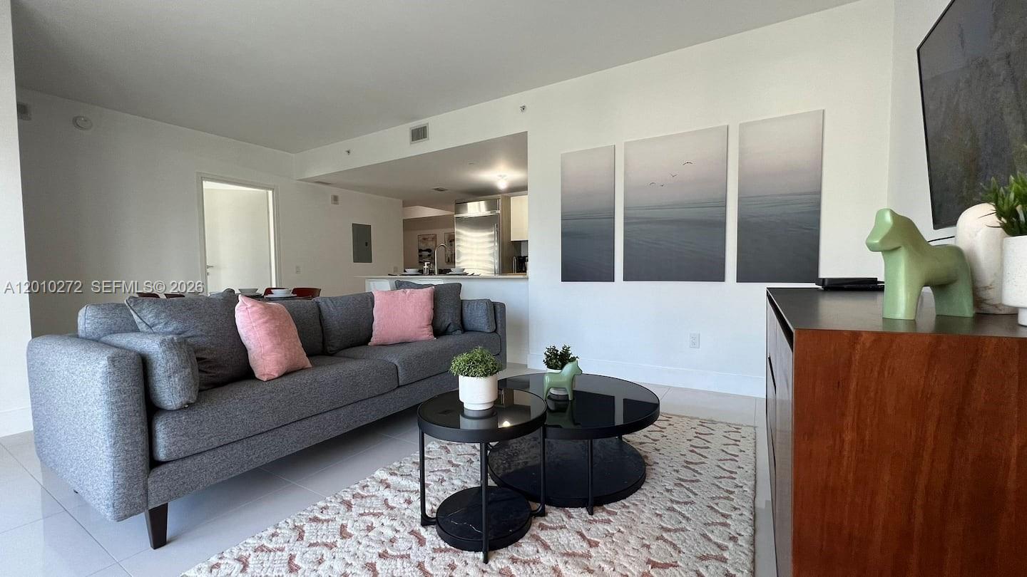 A living room features a gray sofa, two round coffee tables, and wall art — 1300 Brickell Bay Dr # 3400, Miami FL 33131, MIAMI, FL
