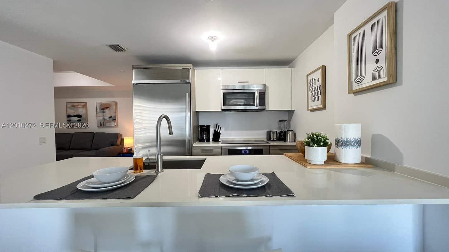 A modern kitchen features white cabinets, stainless steel appliances, and a central island with seating — 1300 Brickell Bay Dr # 3400, Miami FL 33131, MIAMI, FL