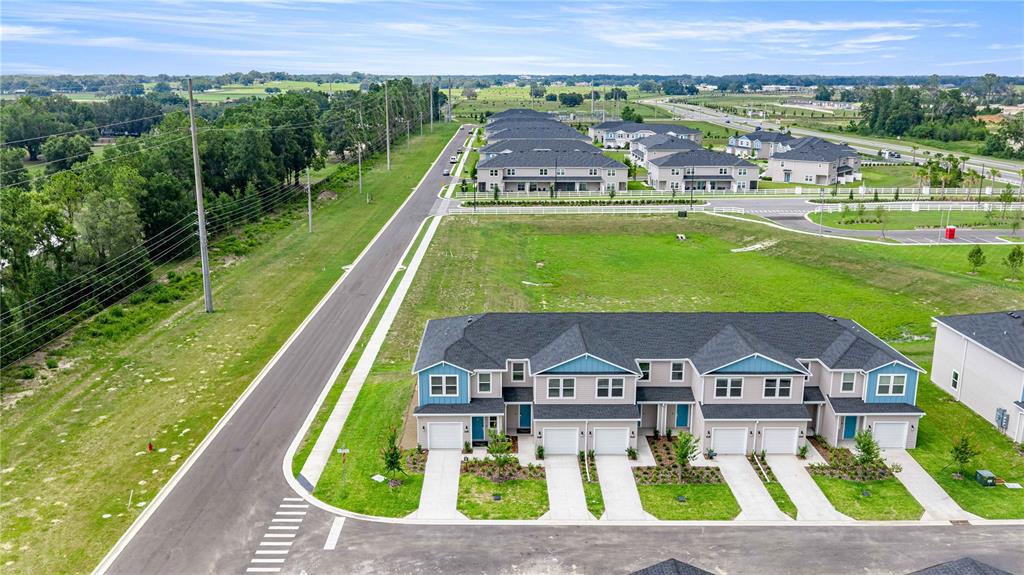 An aerial view shows a row of newly constructed townhomes with garages and paved driveways — 4969 SW 83RD PLACE, OCALA, FL