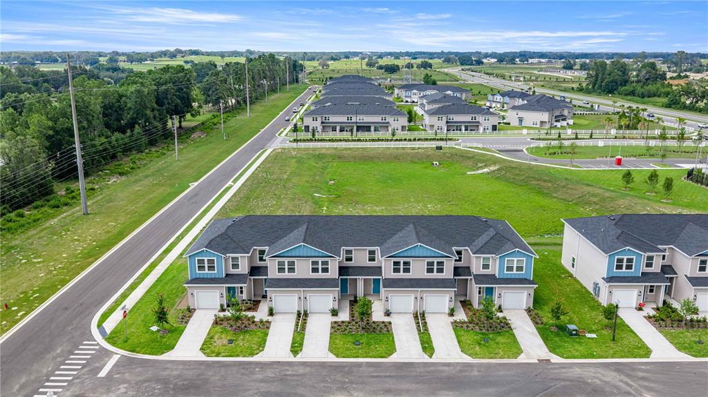 An aerial view shows a row of newly constructed townhomes with attached garages and driveways — 4969 SW 83RD PLACE, OCALA, FL