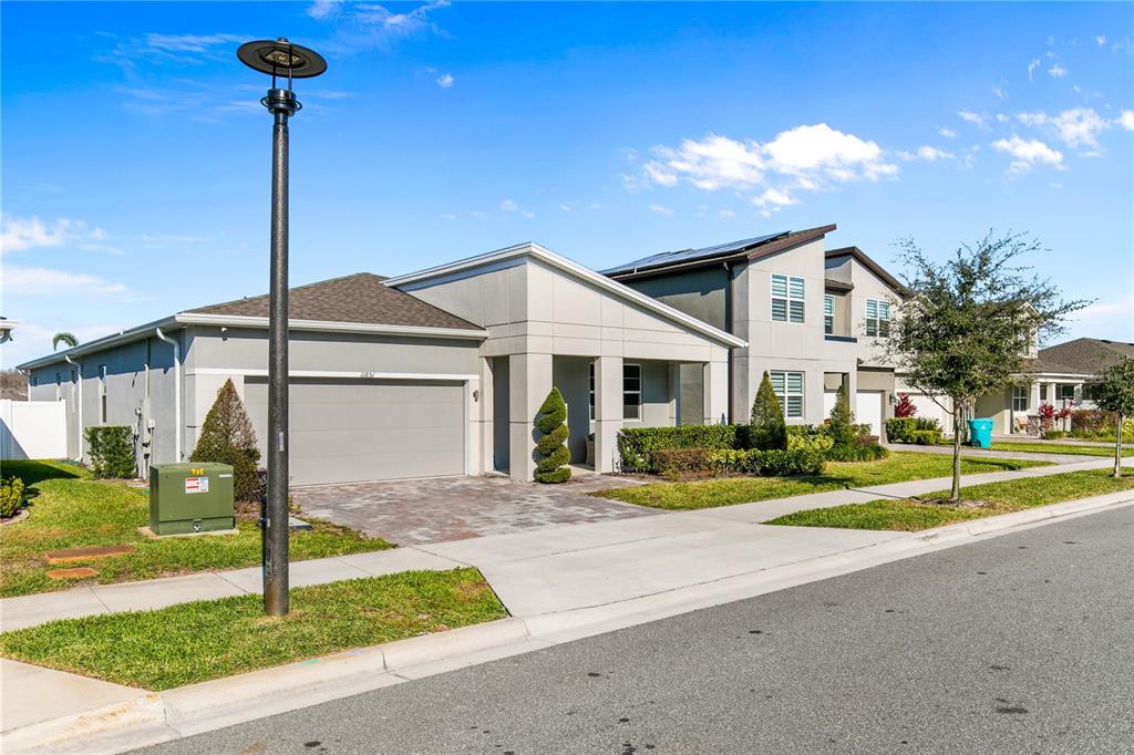 A modern single-story house with a gray garage and a paved driveway under a blue sky — 11851 SUNSAIL AVENUE, ORLANDO, FL
