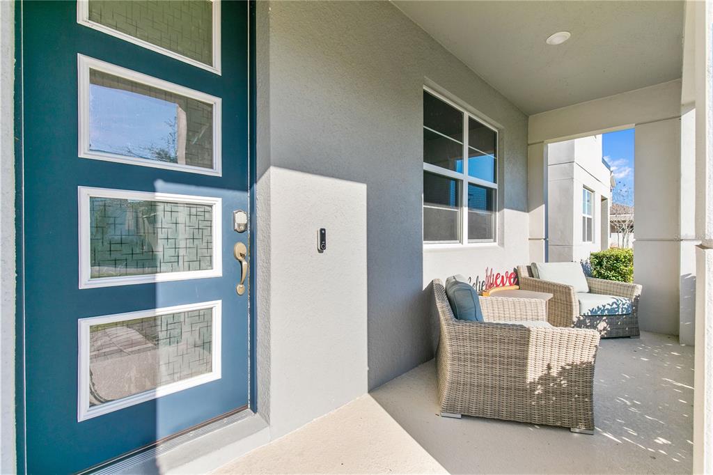 A covered front porch features a blue door with glass panels and two wicker chairs — 11851 SUNSAIL AVENUE, ORLANDO, FL