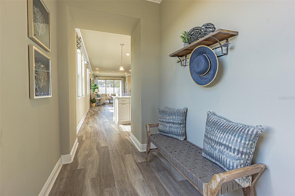 A hallway with wood-look flooring, a bench with two pillows, and a wall-mounted shelf — 9429 HIGHLAND HILLS DRIVE, HUDSON, FL
