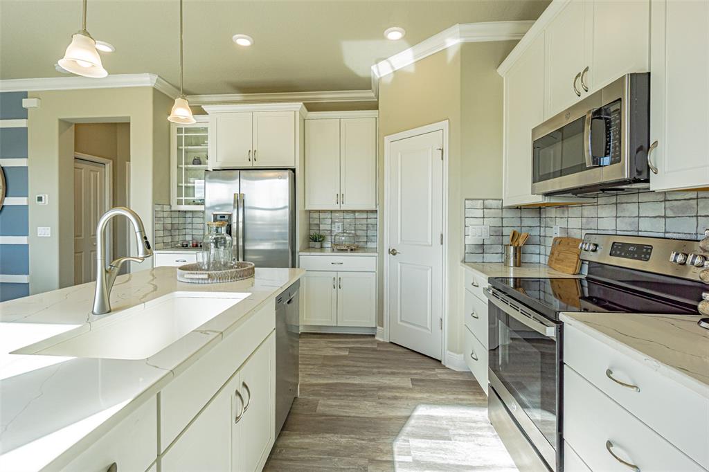 A modern kitchen features white cabinetry, quartz countertops, stainless steel appliances, and a center island — 9429 HIGHLAND HILLS DRIVE, HUDSON, FL