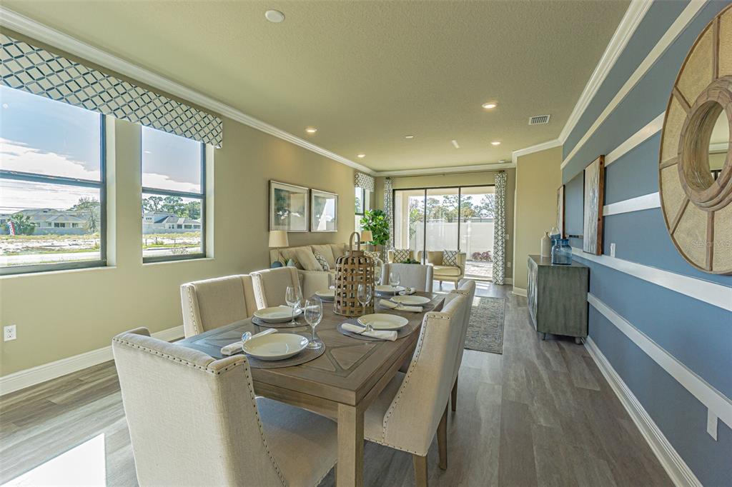 A dining area with a wooden table and upholstered chairs sits before a living space — 9429 HIGHLAND HILLS DRIVE, HUDSON, FL