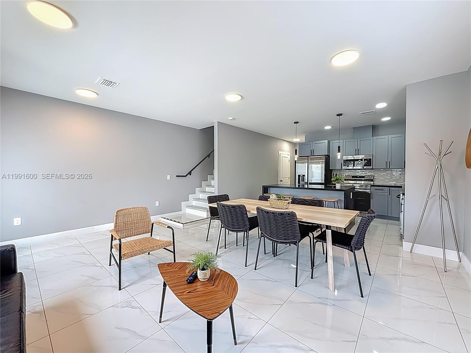 An open-plan living and dining area features gray walls, white tile floors, and a kitchen — 1220 & 1222 NW 30th St, Miami FL 33142, MIAMI, FL