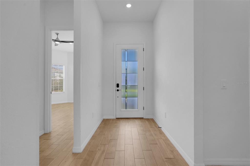 A bright entryway features light wood-look tile flooring and a white door with glass panels — 10393 PARK ESTATES AVENUE, ORLANDO, FL