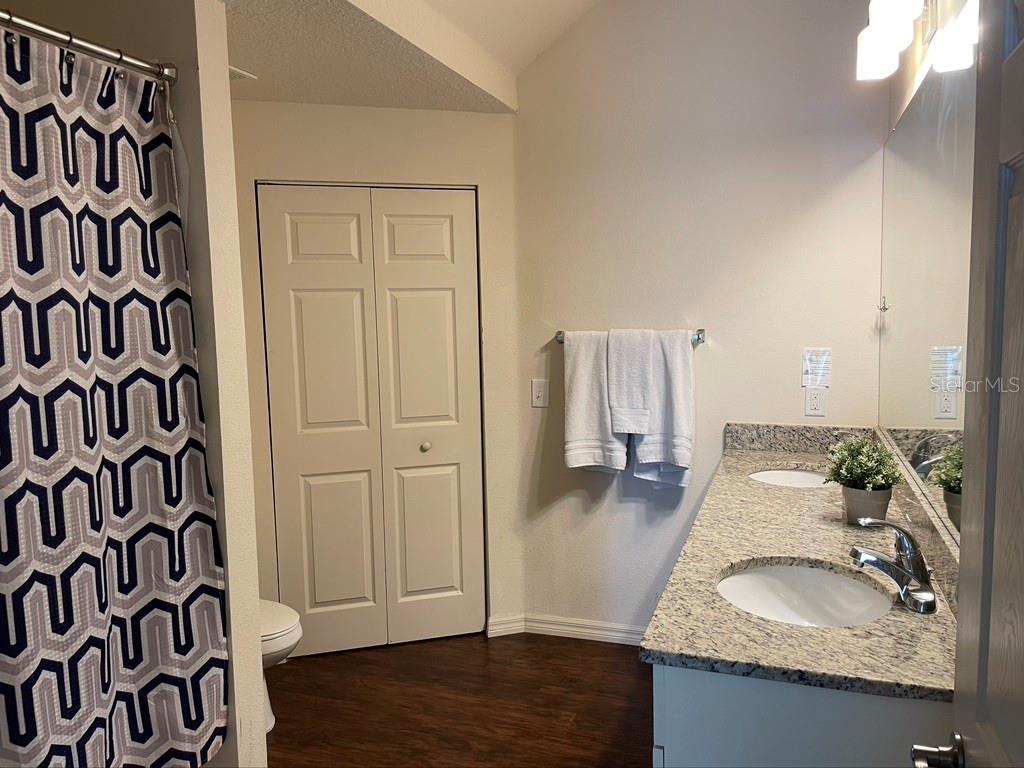 A bathroom features a double vanity with granite countertops, a shower curtain, and a closet — 9004 SHINE DRIVE, KISSIMMEE, FL