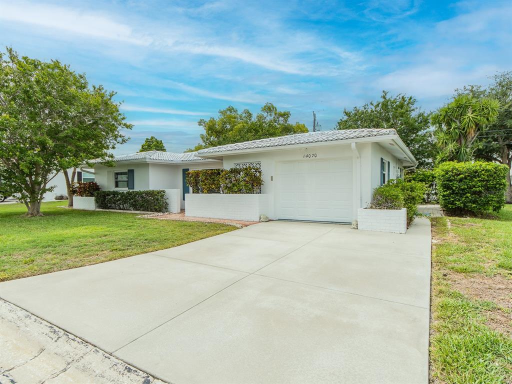 A single-story white house with a garage and a concrete driveway under a blue sky — 14070 90TH AVENUE, SEMINOLE, FL
