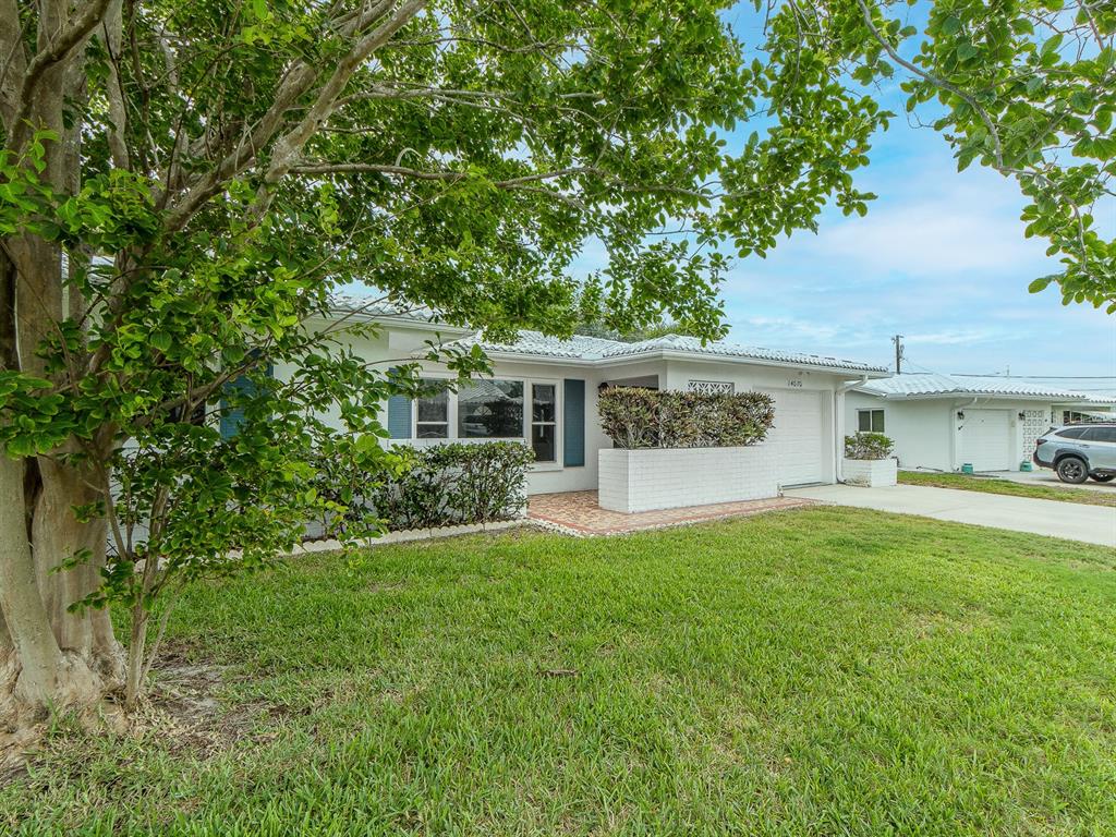 A single-story white house with a tiled roof, a front lawn, and a paved driveway — 14070 90TH AVENUE, SEMINOLE, FL