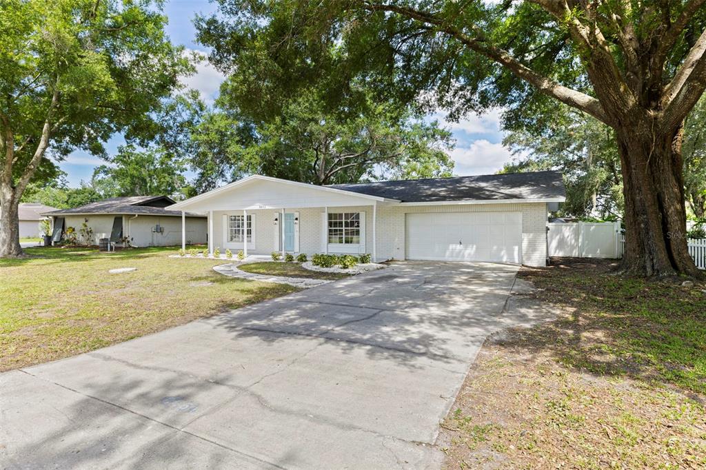 A single-story white brick house with a front-facing garage and a large tree in front — 3651 GREATWOOD COURT, LAND O LAKES, FL