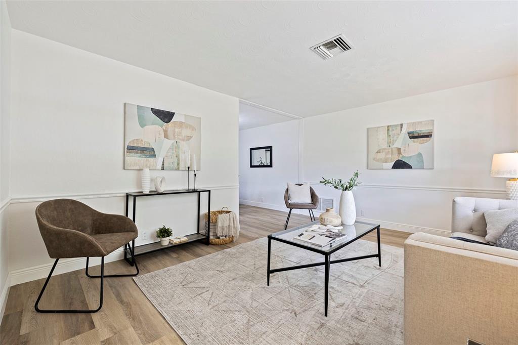 A living room features light wood floors, a glass coffee table, and two abstract paintings — 3651 GREATWOOD COURT, LAND O LAKES, FL