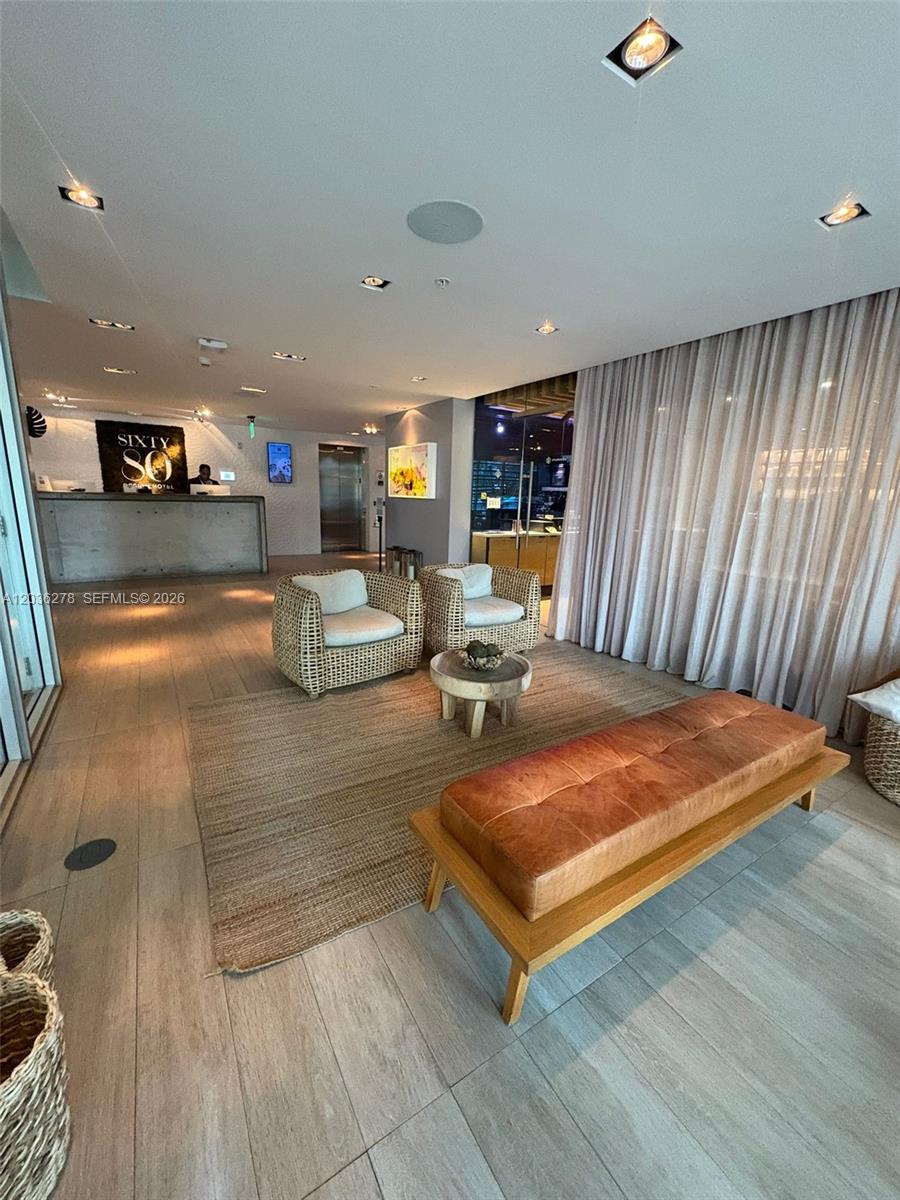 A hotel lobby features a reception desk, wicker armchairs, a leather bench, and floor-to-ceiling curtains — 6080 Collins Ave # 506, Miami Beach FL 33140, MIAMI BEACH, FL