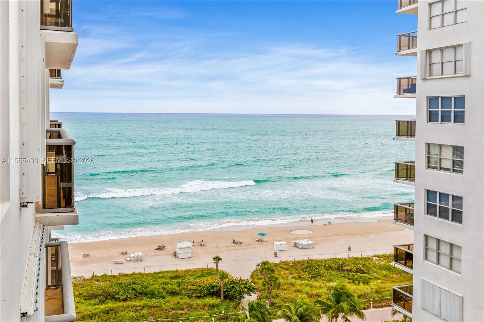An elevated view of a sandy beach and ocean framed by two high-rise apartment buildings — 6039 Collins Ave # 1206, Miami Beach FL 33140, MIAMI BEACH, FL