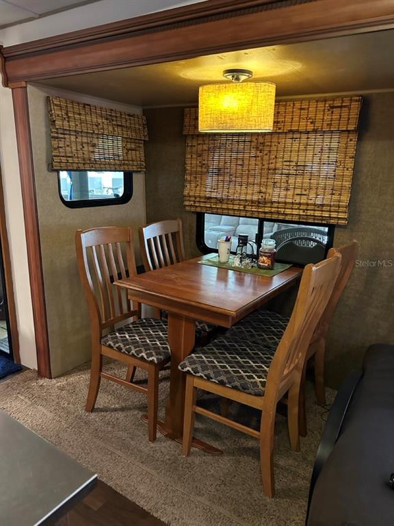 A dining area in an RV features a wooden table, four chairs, and bamboo shades — 25208 NE 143RD STREET, SALT SPRINGS, FL