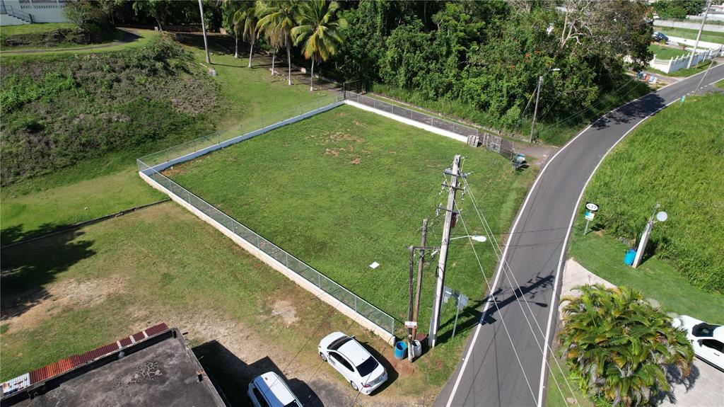 An aerial view shows a fenced, rectangular grassy lot adjacent to a paved road — 637ST BO MIRAFLORES #8-A, ARECIBO, PR