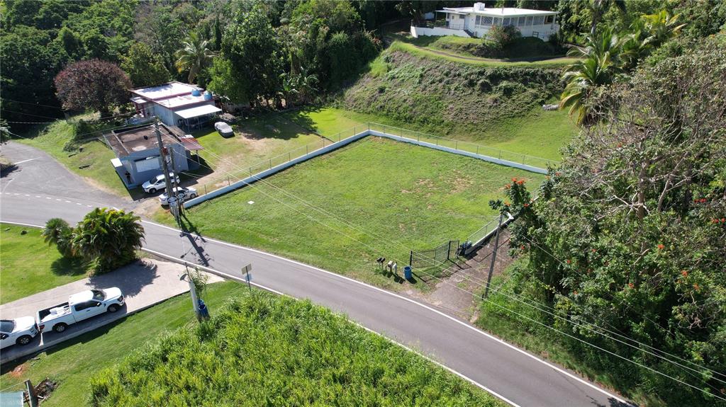 An aerial view shows a fenced, rectangular grassy lot situated next to a paved road — 637ST BO MIRAFLORES #8-A, ARECIBO, PR