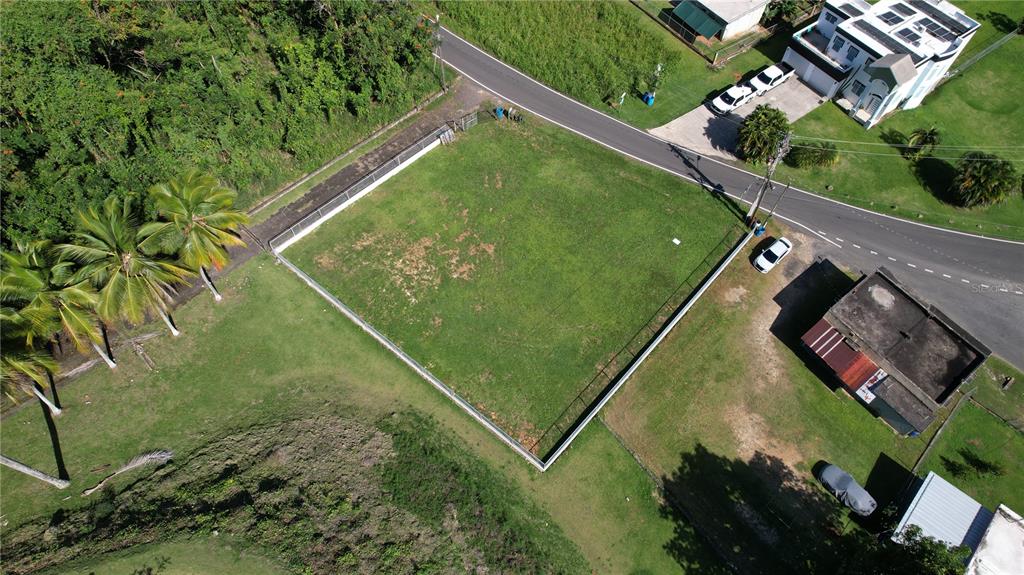 An aerial view shows a fenced, rectangular grassy lot situated next to a paved road — 637ST BO MIRAFLORES #8-A, ARECIBO, PR