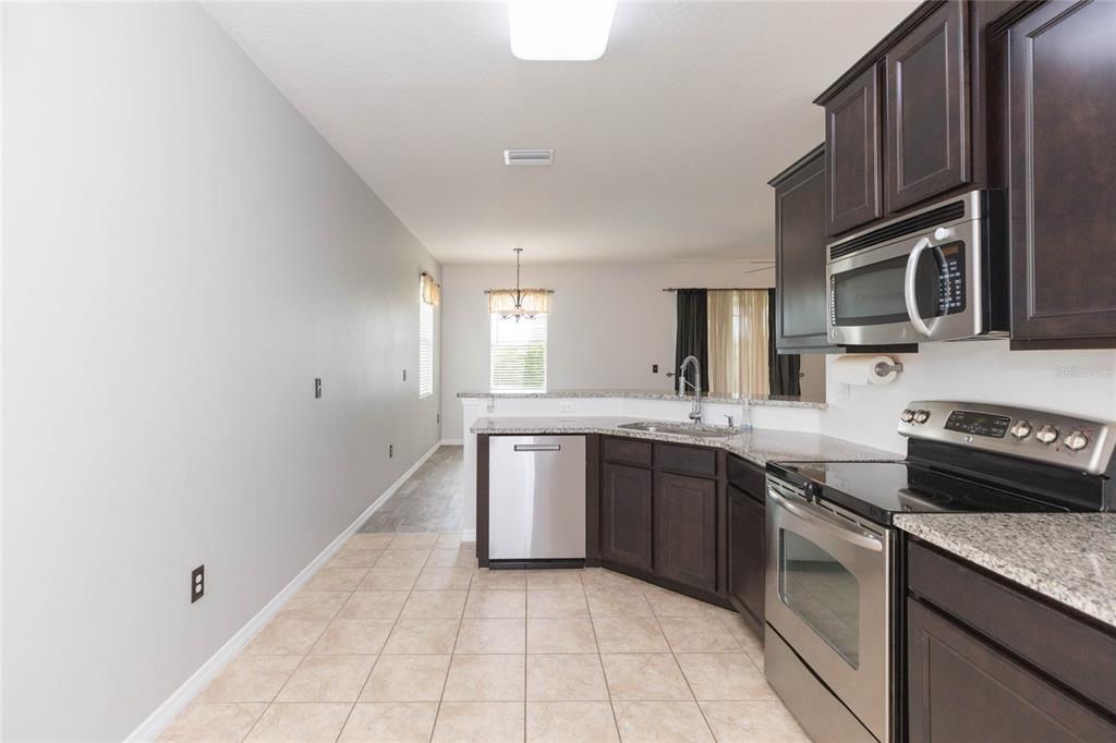 A kitchen with dark wood cabinets, stainless steel appliances, and tile flooring — 36108 LAGUNA HILLS CIRCLE, ZEPHYRHILLS, FL