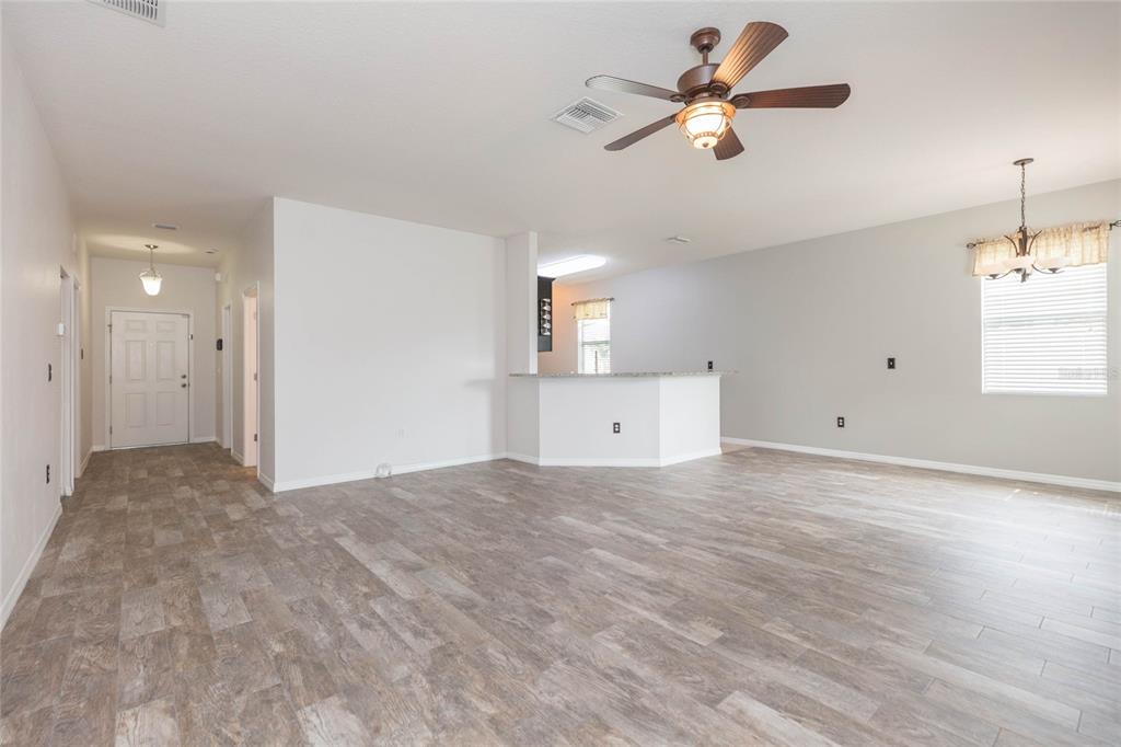 An open-concept living area features light wood-look tile flooring, a ceiling fan, and a kitchen island — 36108 LAGUNA HILLS CIRCLE, ZEPHYRHILLS, FL