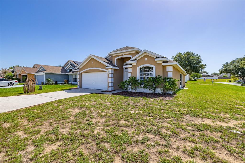 A single-story house with a two-car garage and a tan stucco exterior at sunset — 264 LAUREL RIDGE PASS, DAVENPORT, FL