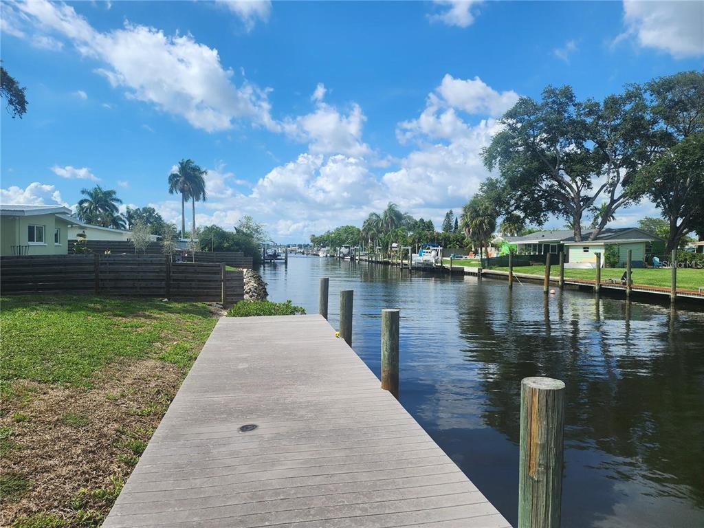 A wooden dock extends into a narrow canal lined with houses and palm trees — 109 21ST STREET NE, BRADENTON, FL
