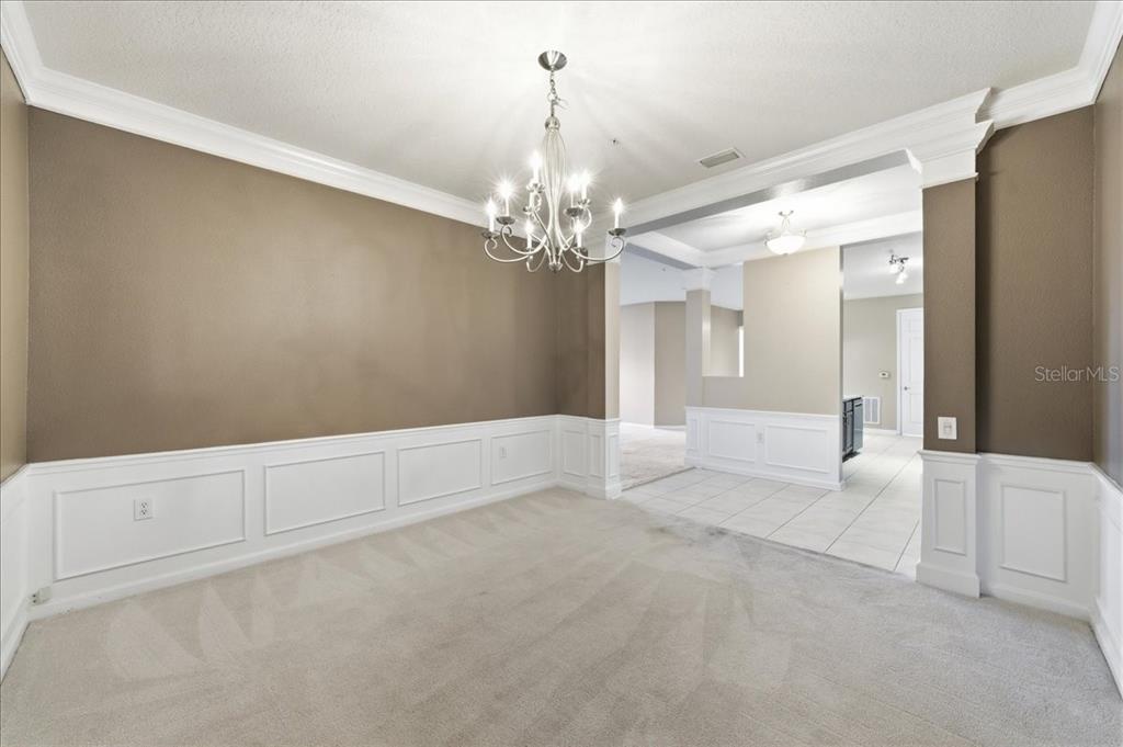 A dining room features tan walls, white wainscoting, a chandelier, and beige carpeting — 7903 SEMINOLE BOULEVARD UNIT 2305, SEMINOLE, FL