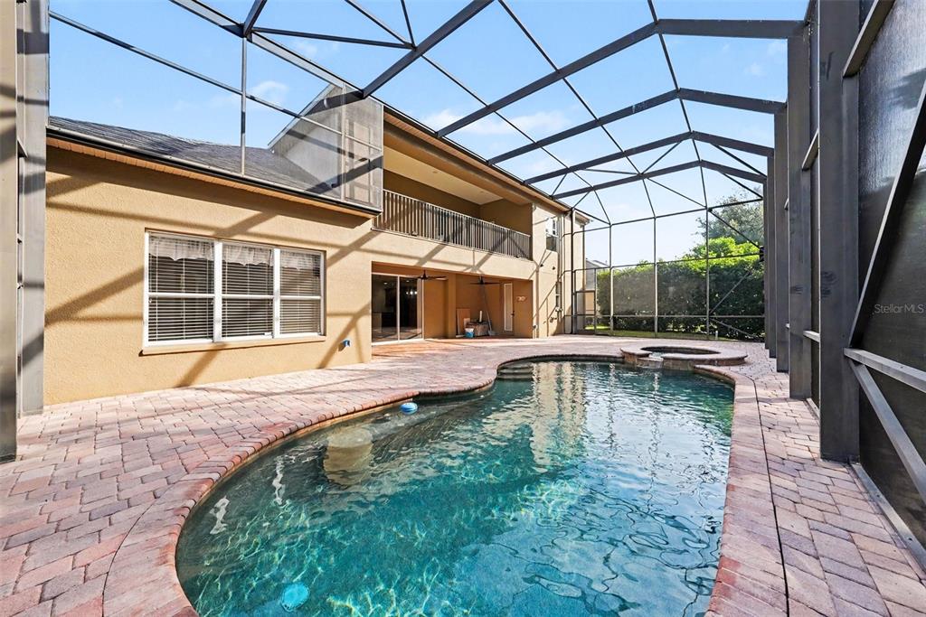 A backyard swimming pool and hot tub enclosed by a screened lanai behind a house — 14906 MAN O WAR DRIVE, ODESSA, FL