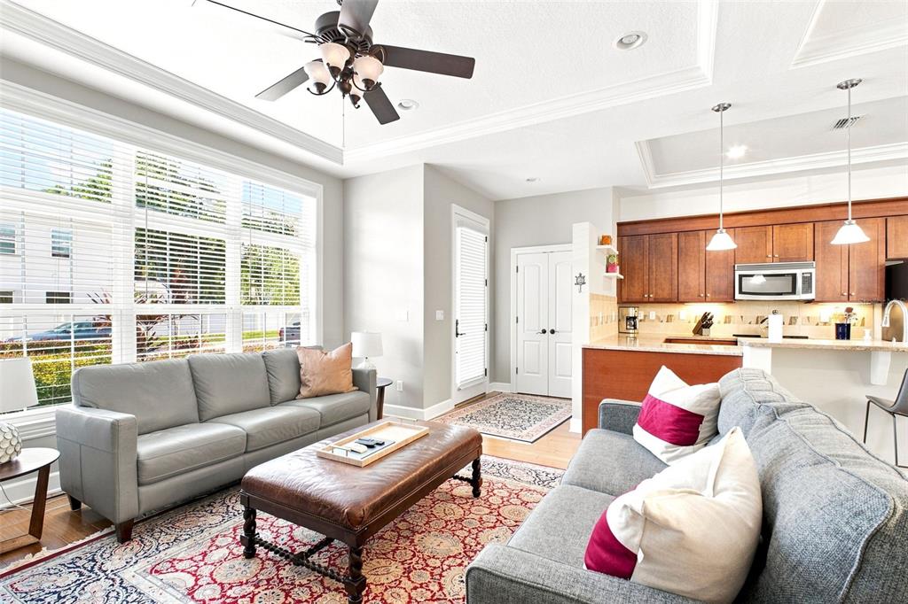 A living room with two grey sofas, a leather ottoman, and an open kitchen area — 2557 W PLATT STREET, TAMPA, FL