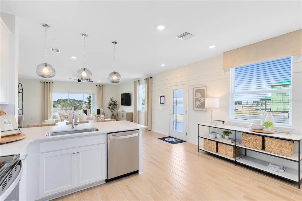 A bright kitchen with white cabinets, stainless steel appliances, and wood-look tile flooring — 4416 CHESTER SPRINGS BOULEVARD, DAVENPORT, FL