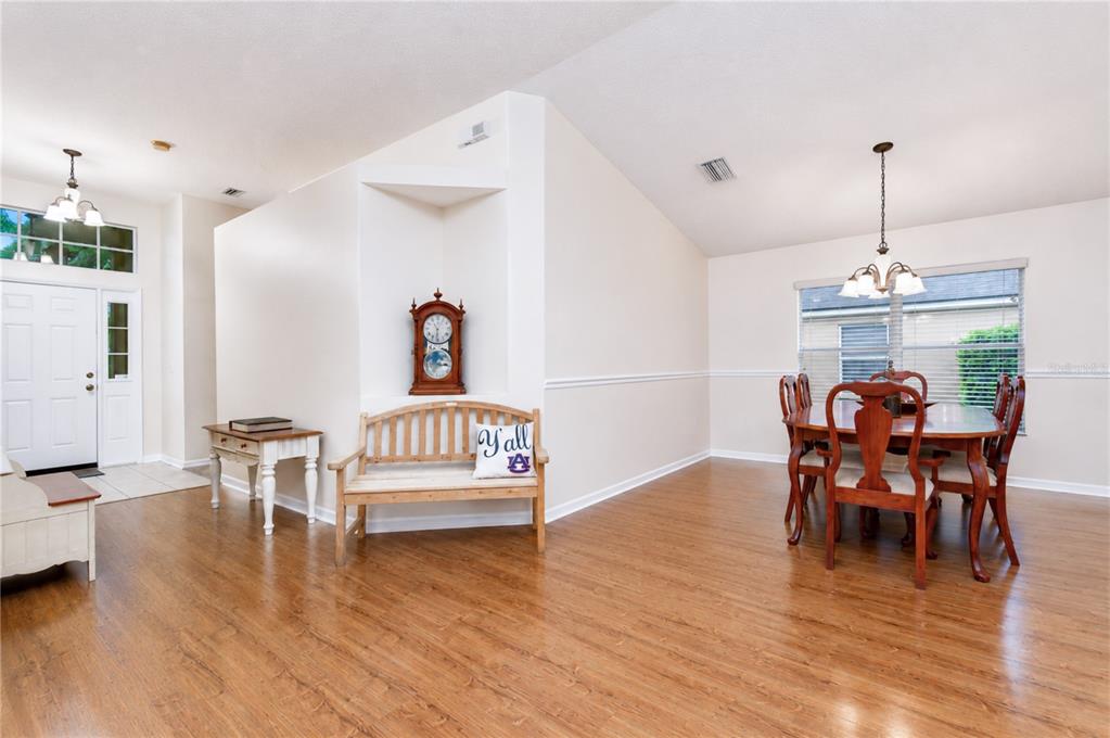 A dining room with wood flooring, a wooden bench, a grandfather clock, and a chandelier — 6209 GANNETDALE DRIVE, LITHIA, FL