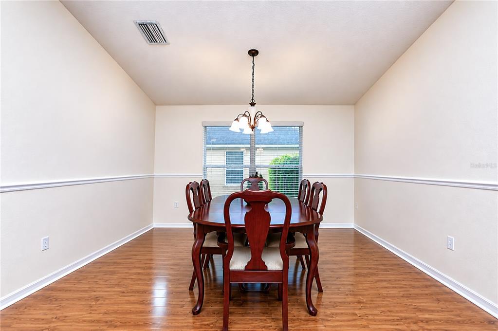 A dining room features a wooden table, six chairs, a chandelier, and wood-look flooring — 6209 GANNETDALE DRIVE, LITHIA, FL