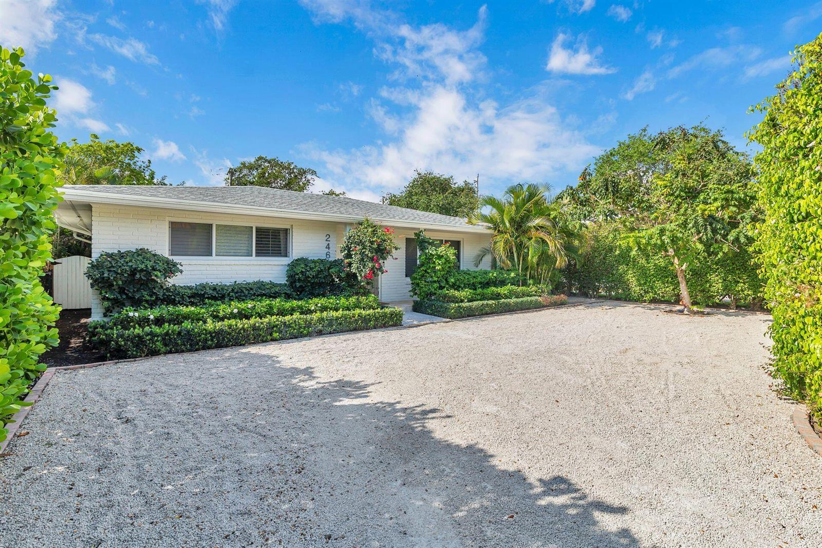 A single-story white brick house with a gravel driveway and lush landscaping under a blue sky — 246 Gray Street, West Palm Beach FL 33405, WEST PALM BEACH, FL