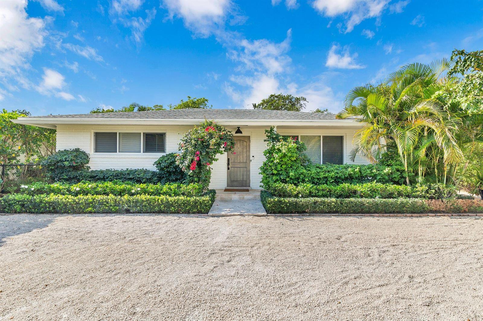 A single-story white house with a gravel driveway and lush landscaping under a blue sky — 246 Gray Street, West Palm Beach FL 33405, WEST PALM BEACH, FL