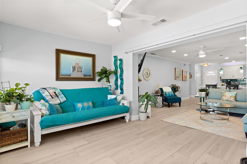 A bright living room features a turquoise futon, light wood flooring, and an open layout — 1898 SHORE DRIVE S UNIT 319, SOUTH PASADENA, FL
