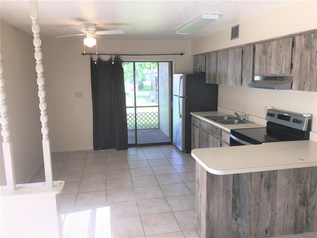 A kitchen with wood-look cabinets and a breakfast bar opens to a tiled dining area — 2806 46TH AVENUE DRIVE W, BRADENTON, FL