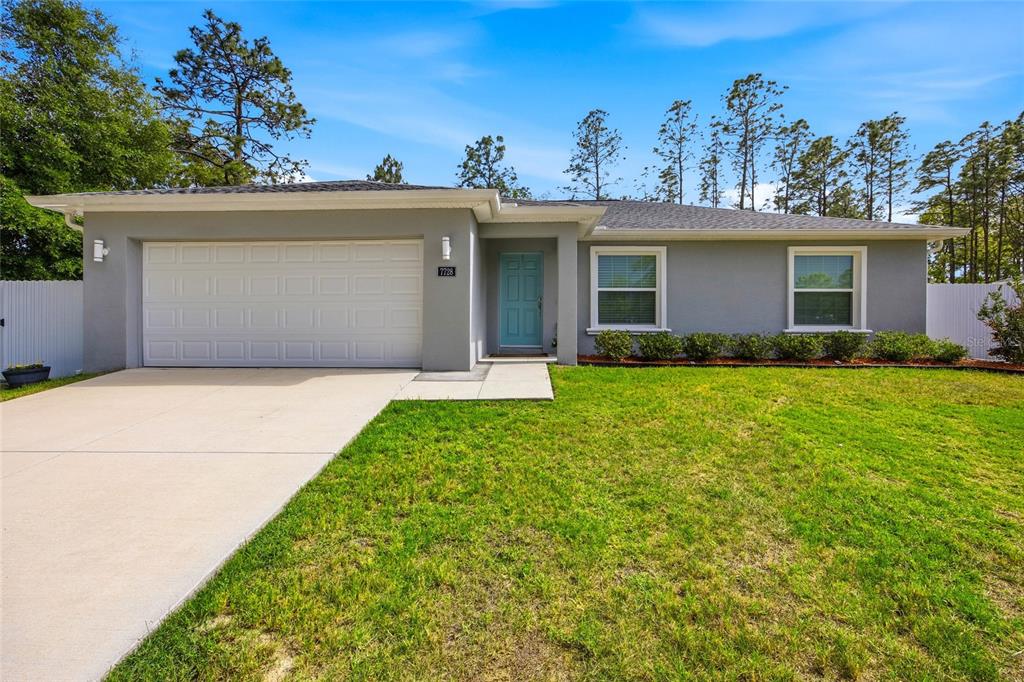 A single-story house with a gray exterior, a two-car garage, and a light blue door — 7728 SW 132ND PLACE, OCALA, FL