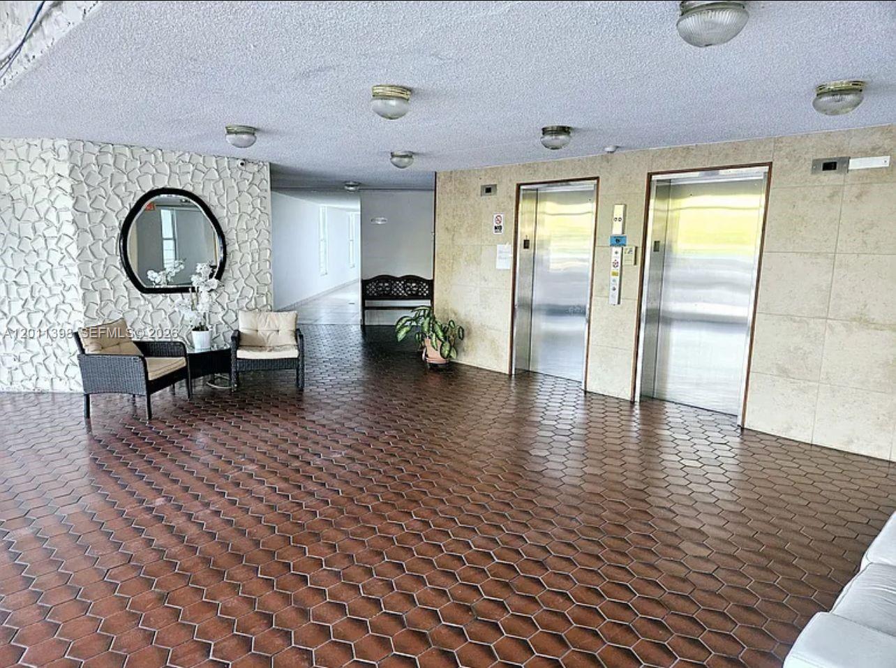 A building lobby features two elevators, a tiled floor, and a seating area with chairs — 9682 Fontainebleau Blvd # 207, Miami FL 33172, MIAMI, FL