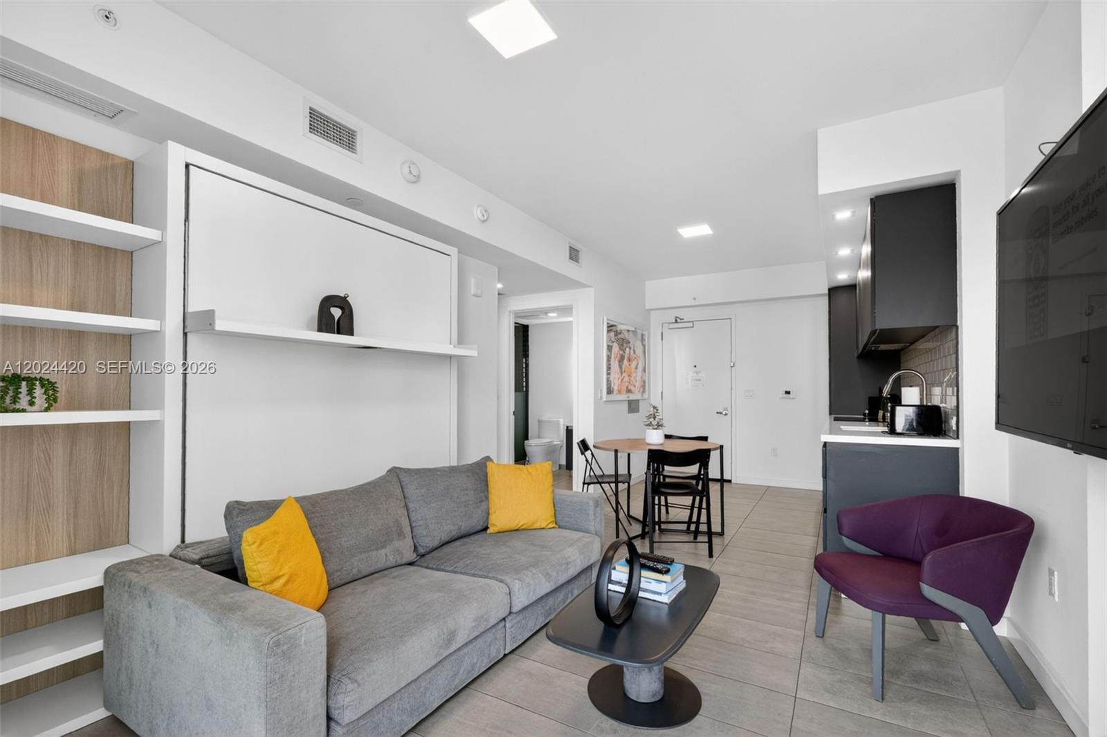 A studio apartment features a gray sofa, a dining table, and a kitchenette with dark cabinets — 227 NE 2nd St # 2805, Miami FL 33132, MIAMI, FL