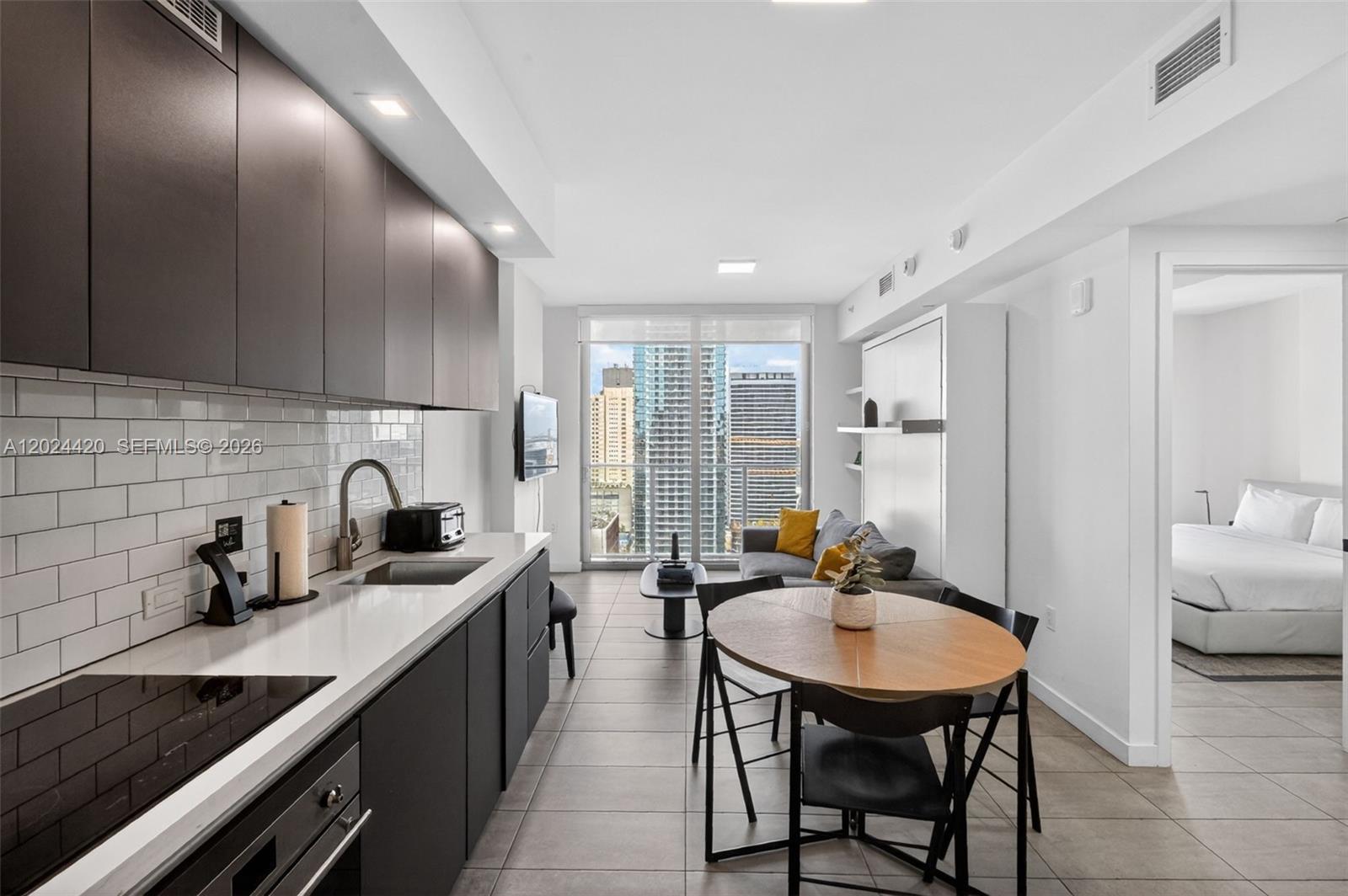 A modern apartment features a kitchen with dark cabinets, a dining area, and a living space — 227 NE 2nd St # 2805, Miami FL 33132, MIAMI, FL