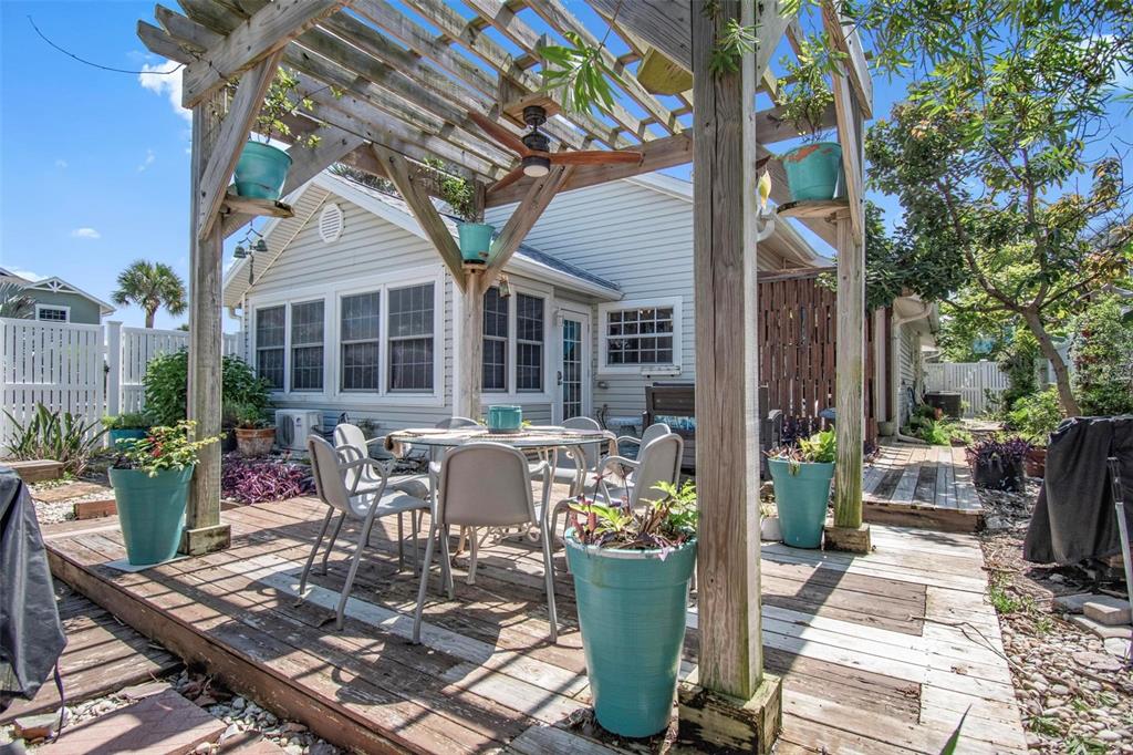 A wooden pergola covers a patio dining set on a weathered deck behind a house — 15 SEA VISTA DRIVE, PALM COAST, FL