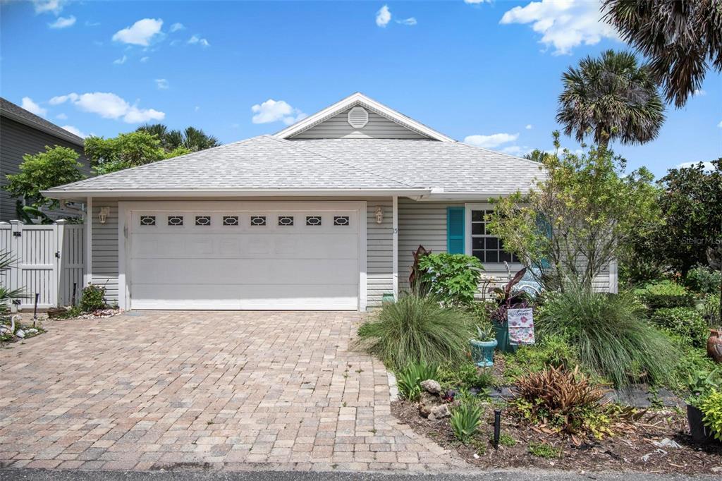 A single-story house with light gray siding, a two-car garage, and a brick paver driveway — 15 SEA VISTA DRIVE, PALM COAST, FL