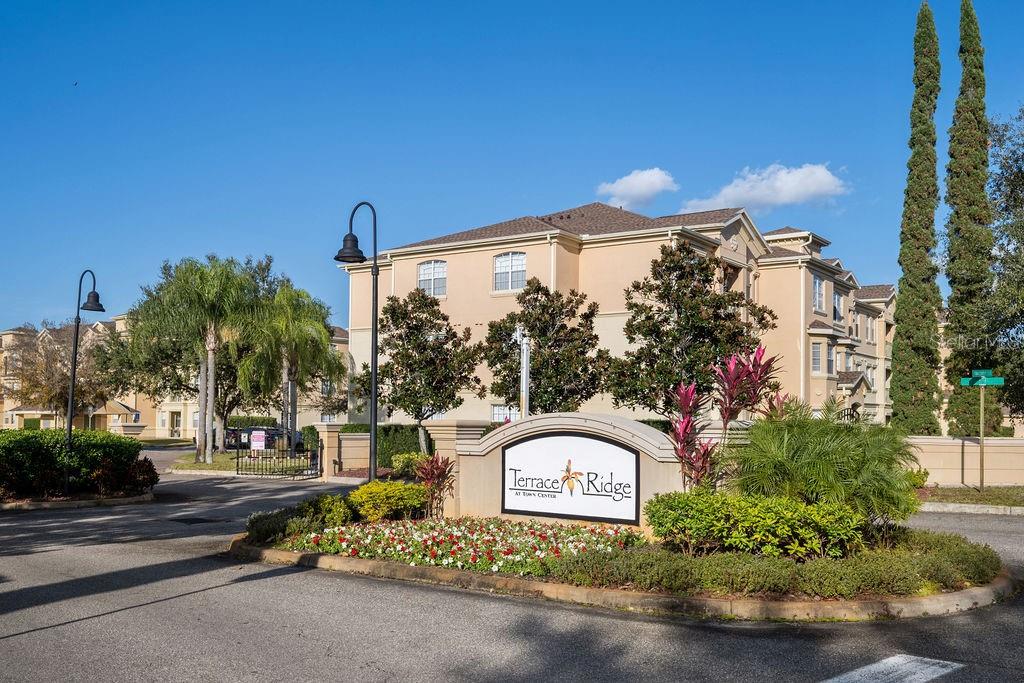 The exterior of the Terrace Ridge apartment complex features a beige building and gated entrance — 302 TERRACE RIDGE CIRCLE UNIT 302, DAVENPORT, FL
