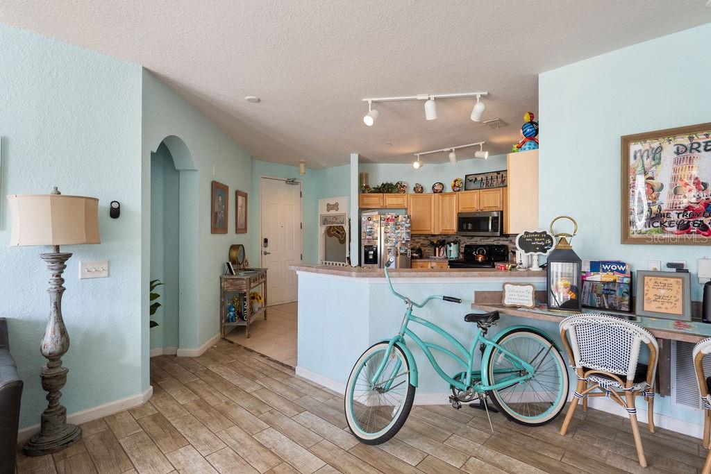 A kitchen with light wood cabinets and a breakfast bar sits behind a turquoise bicycle — 302 TERRACE RIDGE CIRCLE UNIT 302, DAVENPORT, FL