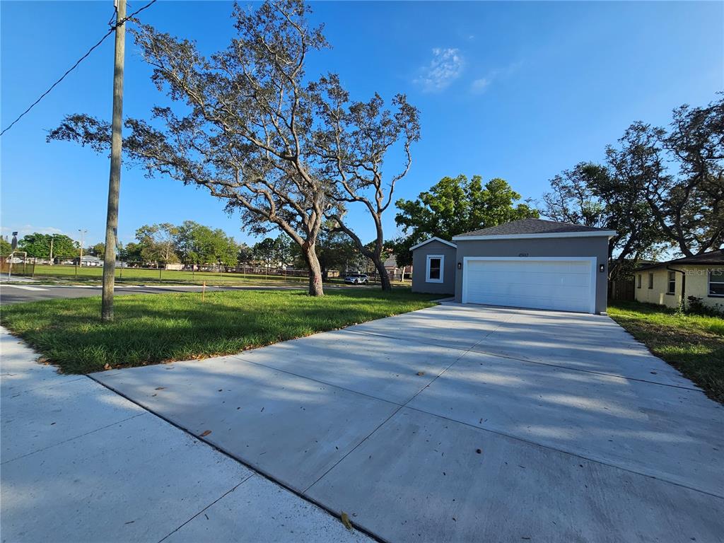 A detached garage with a white door sits next to a large tree and lawn — 4502 42ND AVENUE N, ST PETERSBURG, FL