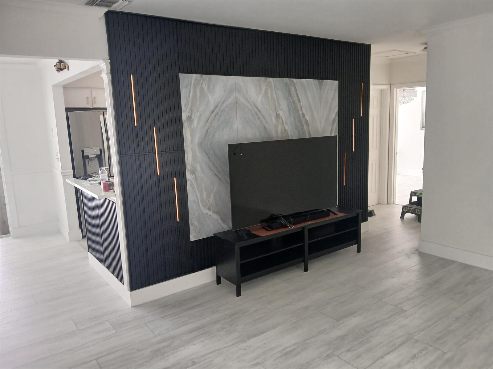A living room features a dark slatted accent wall with integrated lighting and marble paneling — 6641 Miramar Parkway, Miramar FL 33023, MIRAMAR, FL