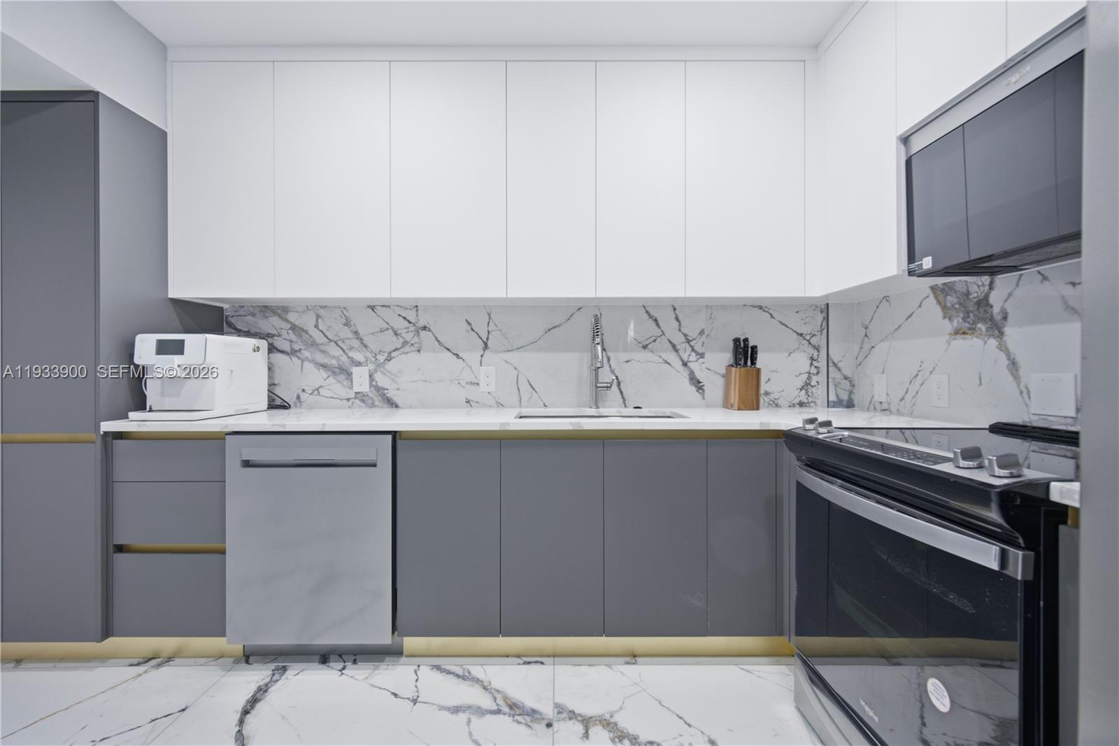 A modern kitchen features white upper cabinets, gray lower cabinets, gold accents, and marble surfaces — 4200 Hillcrest Dr # 802, Hollywood FL 33021, HOLLYWOOD, FL