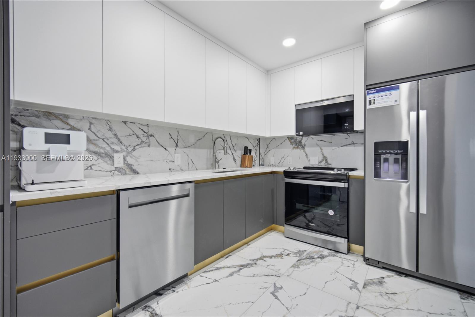 A modern kitchen features white upper cabinets, grey lower cabinets, and marble-patterned surfaces — 4200 Hillcrest Dr # 802, Hollywood FL 33021, HOLLYWOOD, FL
